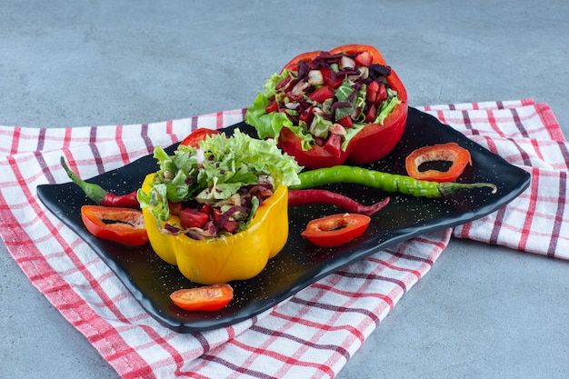 Pepper platter with small salad servings on marble table.