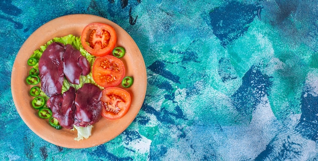 Peperoni, pomodori, lattuga e frattaglie di pollo su un piatto di argilla Foto Gratuite