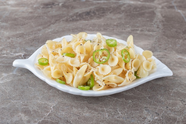 Free photo peppered farfalle pasta on a fancy plate , on the marble surface.