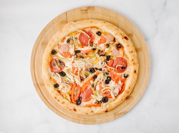 Pepperoni olive pizza on a wooden plate.