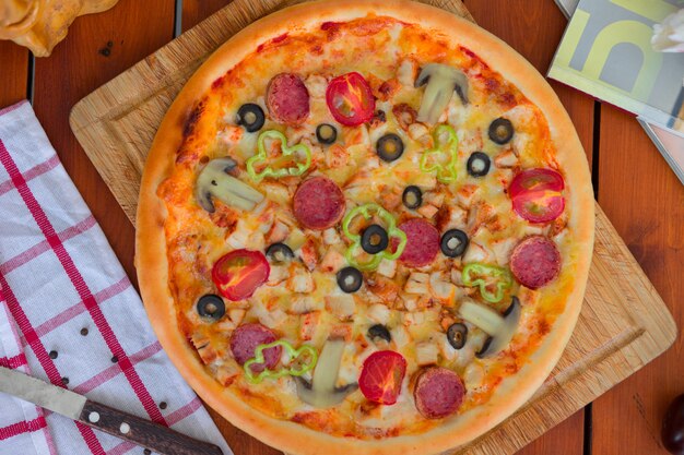 Пицца пепперони с болгарским перцем, ломтиками томатов, грибами и оливками.