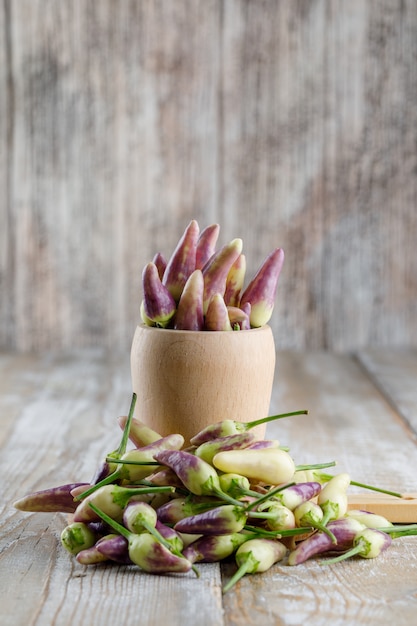 Free photo peppers with cutting board in a vase on wooden,