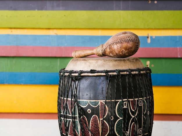 Foto gratuita strumenti a percussione a fianco di una parete a strisce multicolori con copia-spazio