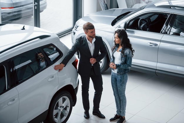 Foto gratuita scelta perfetta. cliente femminile e uomo d'affari barbuto elegante moderno nel salone dell'automobile