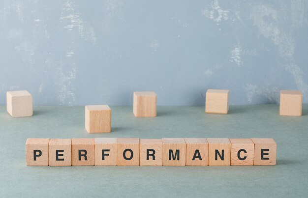 Performance and business concept with wooden blocks with words on it side view.