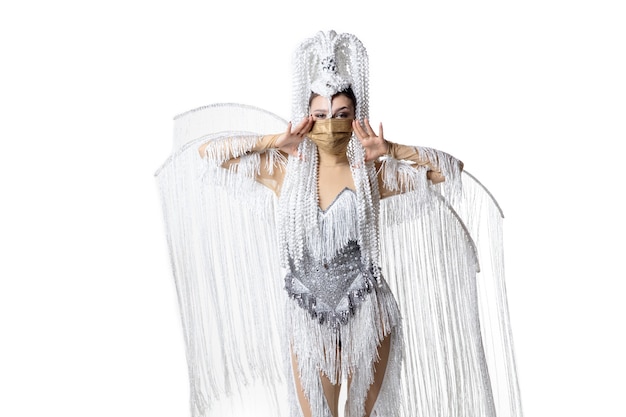 Performing. Beautiful young woman in carnival masquerade costume with white feathers dancing on white background. Concept of holidays celebration, festive time, dance, party, happiness. Copyspace
