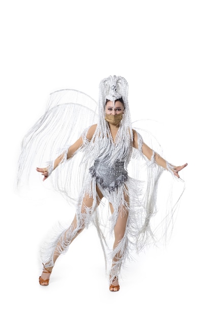 Бесплатное фото Выполнение. красивая молодая женщина в карнавальном маскарадном костюме с белыми перьями, танцующими на белом фоне. концепция празднования праздников, праздничное время, танец, вечеринка, счастье. copyspace