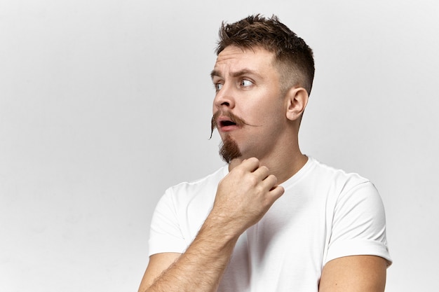 Free photo perplexed emotional hipster guy with handlebar mustache and stubble opening mouth in shock and amazement, surprised with bad shocking news. frustrated astonished bearded man posing in studio