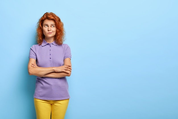 Foto gratuita donna millenaria perplessa con capelli rossi ondulati in posa