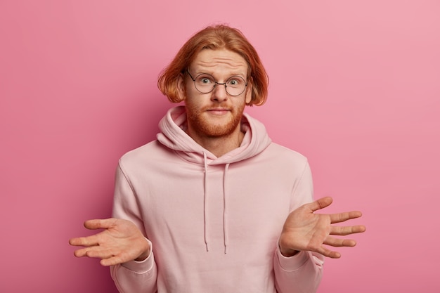 Perplexed unaware man with ginger hair, spreads palms