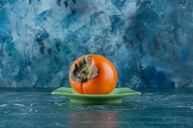 Persimmon fruit on coaster, on the marble table. 