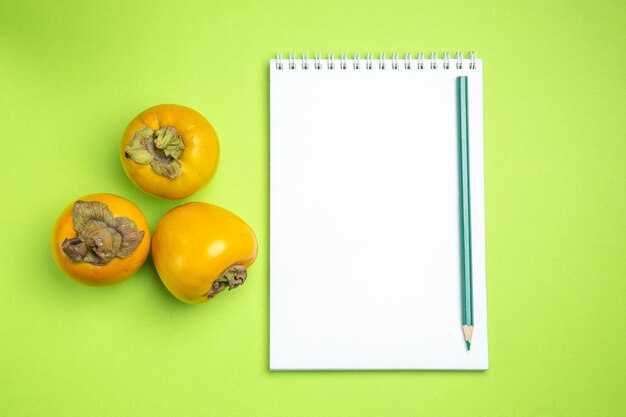 persimmons persimmons pencil white notebook pencil on the green table