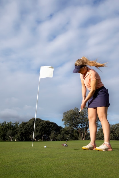 Persona che mira alla bandiera del golf