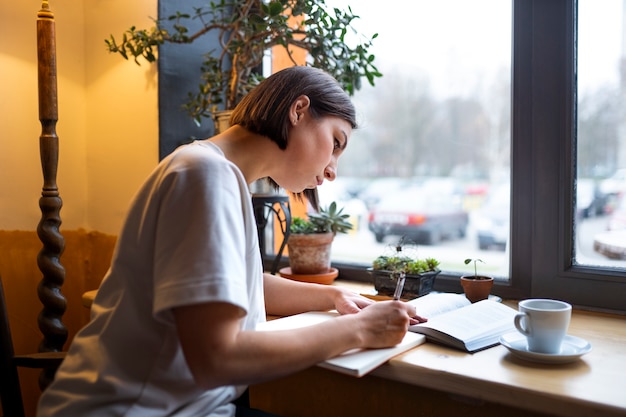 Foto gratuita persona in un caffè che si gode un libro