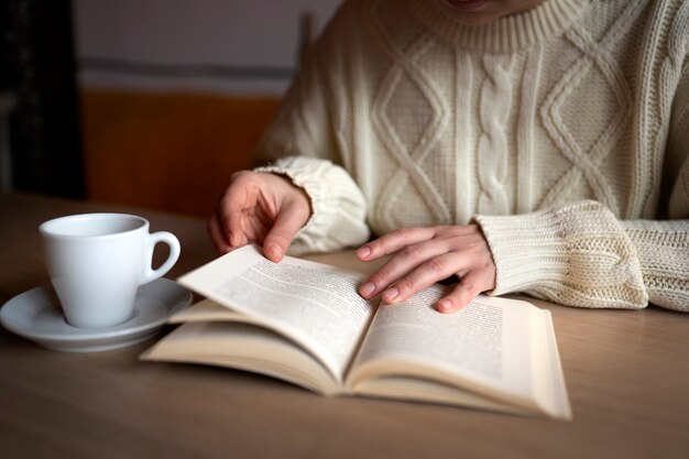 Человек в кафе читает книгу за чашкой кофе