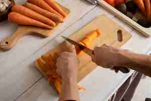 Free photo person chopping carrots in the kitchen