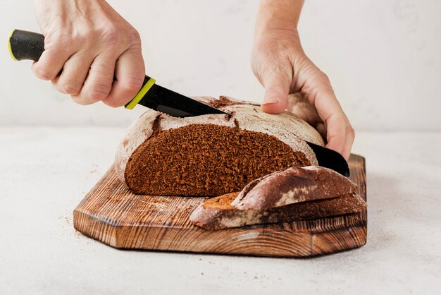 Persona che taglia il pane sul bordo di legno