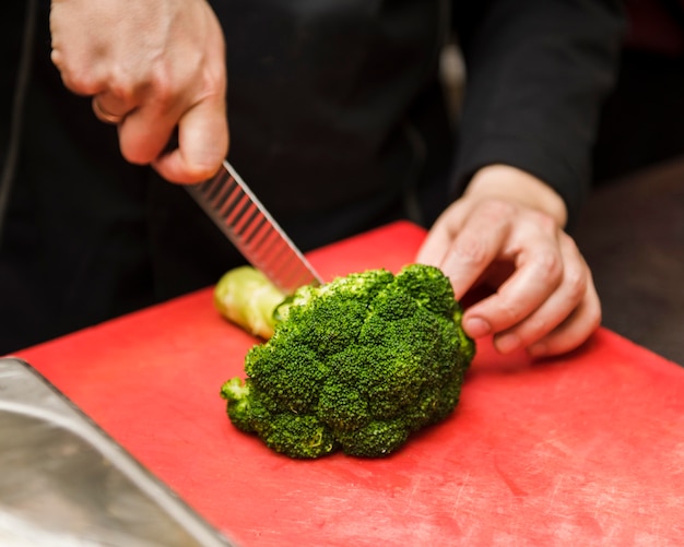 Foto gratuita persona che taglia i broccoli freschi