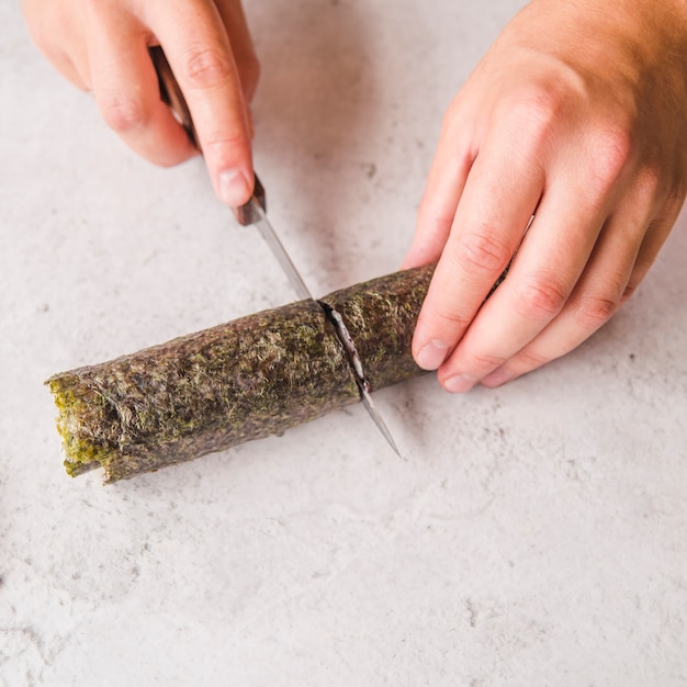 Free photo person cutting sushi roll in half