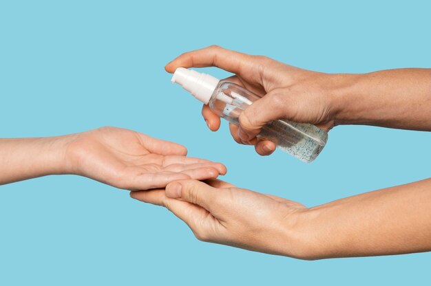 Person disinfecting hands isolated on blue