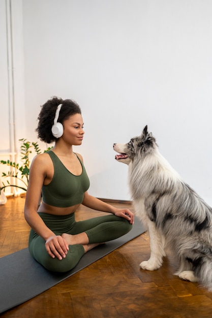 Free photo person doing yoga accompanied by her pet