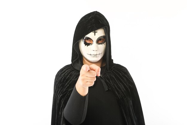 額と黒いマントに十字架が付いた白いマスクをしていて 白い背景にカボチャのジャック オー ランタンを持って指を向けている人 カーニバル ハロウィーン 死者の日のコンセプト プレミアム写真 額と黒いマントに十字架が付いた白いマスクをしていて 白い背景にカボチャのジャック オー ランタンを持って指を向けている人 カーニバル ハロウィーン 死者の日のコンセプト プレミアム写真
