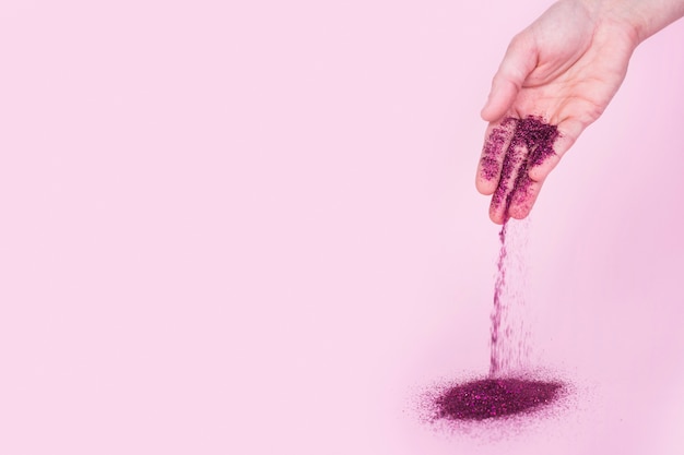 Free photo person dropping bright glitter powder on table