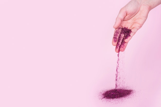 Person dropping bright glitter powder on table