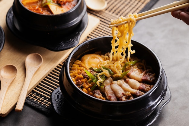 Person eating Chinese food from a black plate with chopsticks