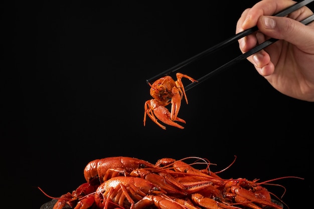 Person eating crawfish with chopsticks