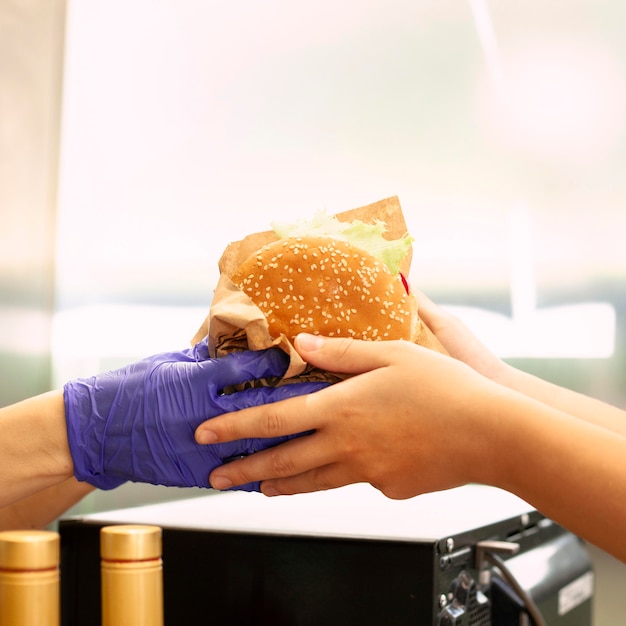 Foto gratuita persona che ottiene hamburger dal lavoratore di fast food