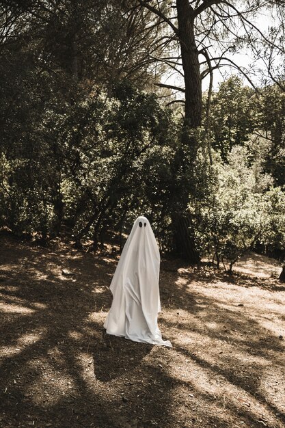Person in ghost costume walking in forest
