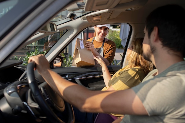 Foto gratuita persona che effettua un ordine a un cliente durante un ritiro a bordo strada