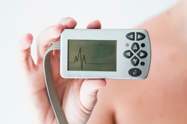 Person hand holding monitor with cardiogram 