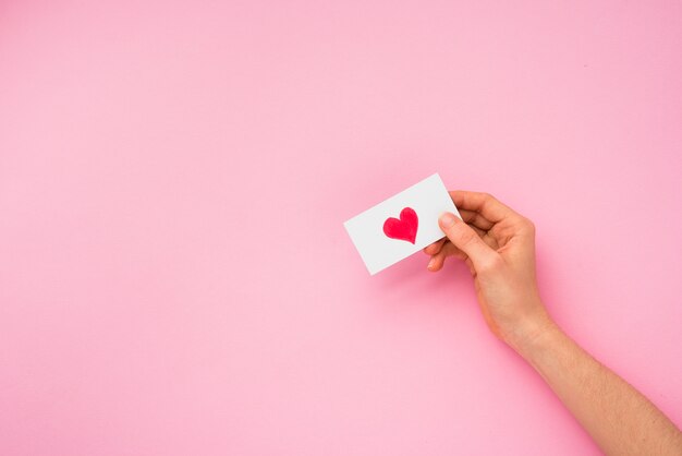 Person hand holding paper with heart picture 