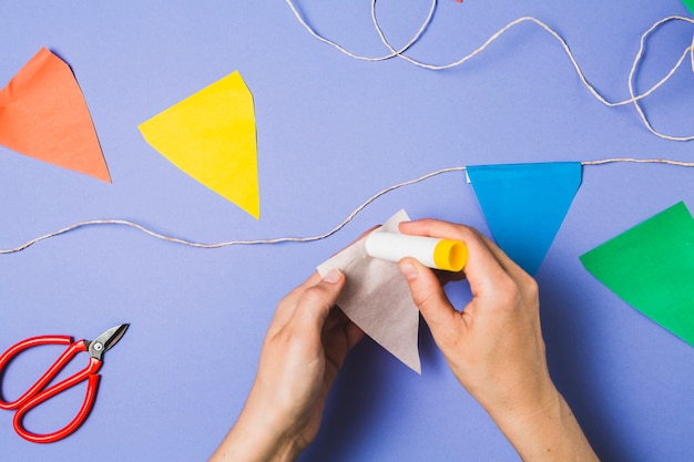 A person hand sticking bunting paper with glue stick