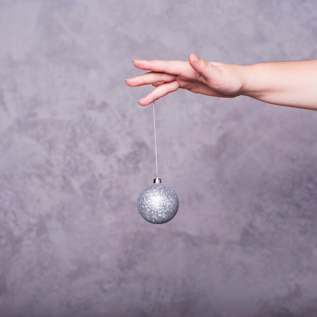 Person hand with Christmas ball on thread
