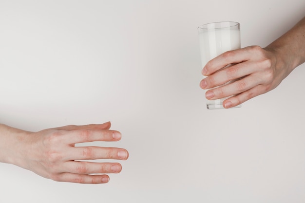 Free photo a person handing a glass of milk to another one