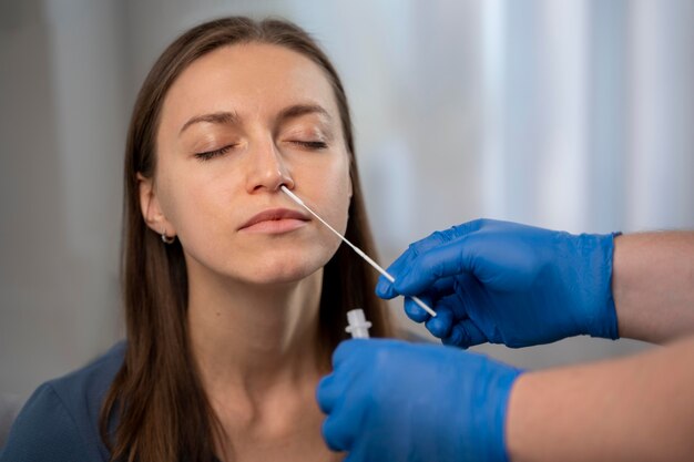 Person helping a woman taking a covid test at home