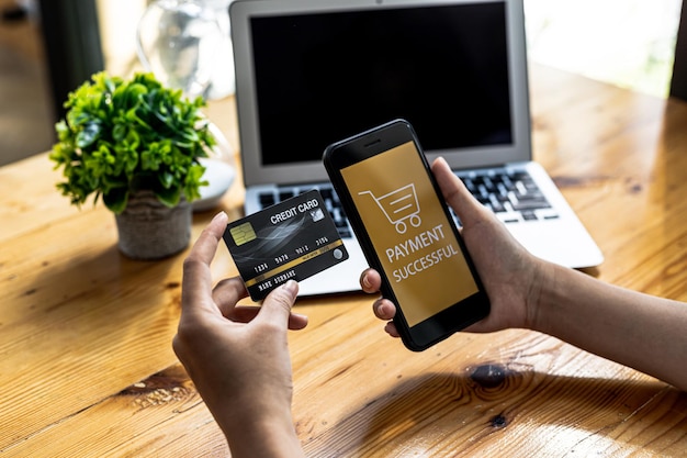 온라인 결제 웹사이트의 화면에서 스마트폰을 들고 스마트폰을 사용하여 온라인으로 신용 카드를 통해 상품을 결제하는 사람. 스마트폰을 사용하여 신용 카드를 통해 제품 비용을 지불하는 개념.