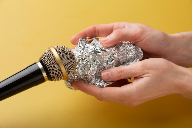 Человек, держащий алюминиевую фольгу рядом с микрофоном для asmr