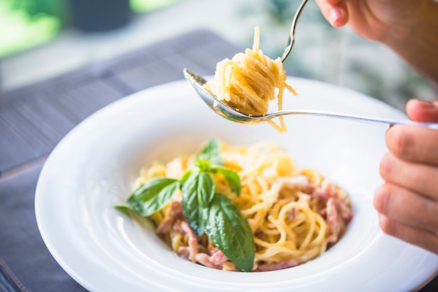 食欲をそそるスパゲッティを持っている人がフォークに巻き込まれた