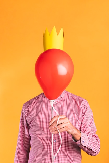 Free photo person holding a balloon on orange background