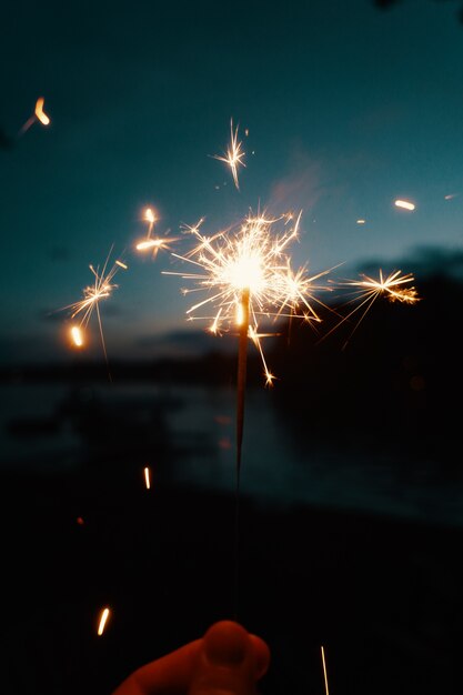 Person holding Bengal lights or sparklers on a dark blurry background