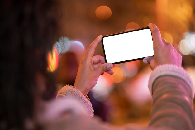 Person holding a blank smartphone with bokeh effect around