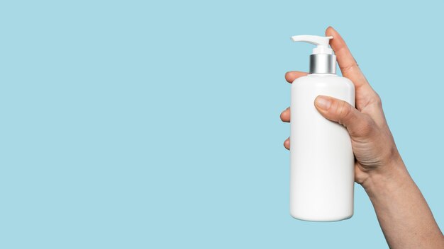 person holding a bottle of liquid soap with copy space