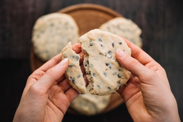 Person holding broken cookie in hands 