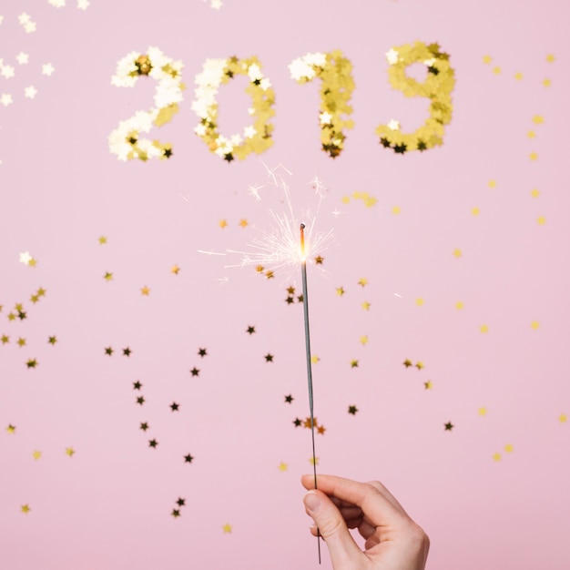 Free photo person holding burning bengal fire above 2019 inscription