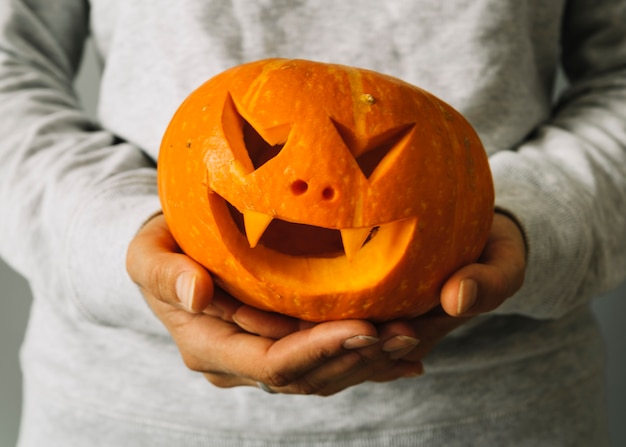 Person holding carved Halloween pumpkin