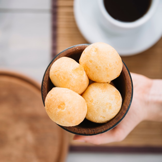 Free photo person holding cheese balls in wooden bowl